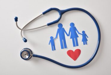 Stethoscope surrounding a paper cutout family – family medicine concept